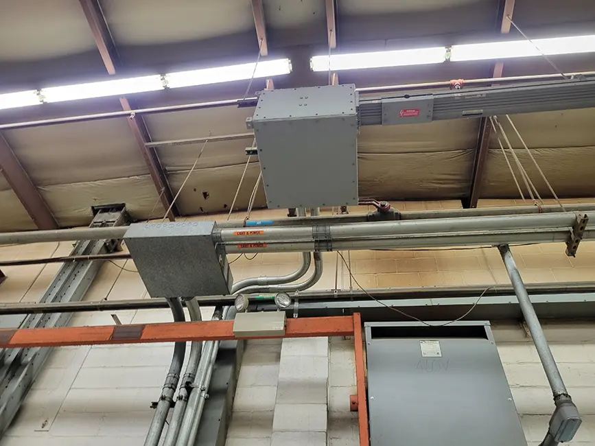 Inside view of ceiling area inside large industrial manufacturing warehouse with electrical wiring.